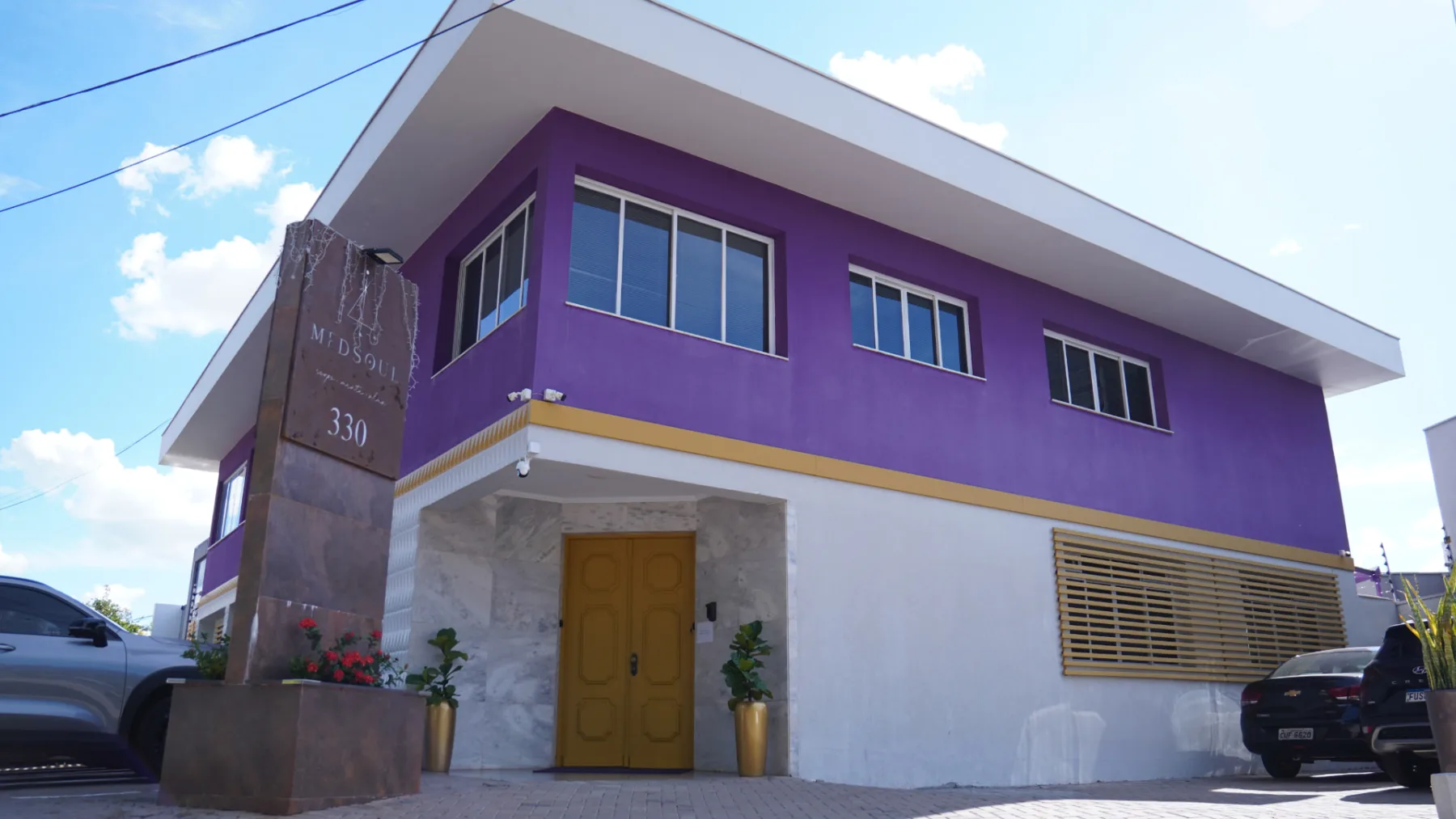 Fachada da MedSoul Clinic — prédio roxo com detalhes brancos e dourados, sob céu azul