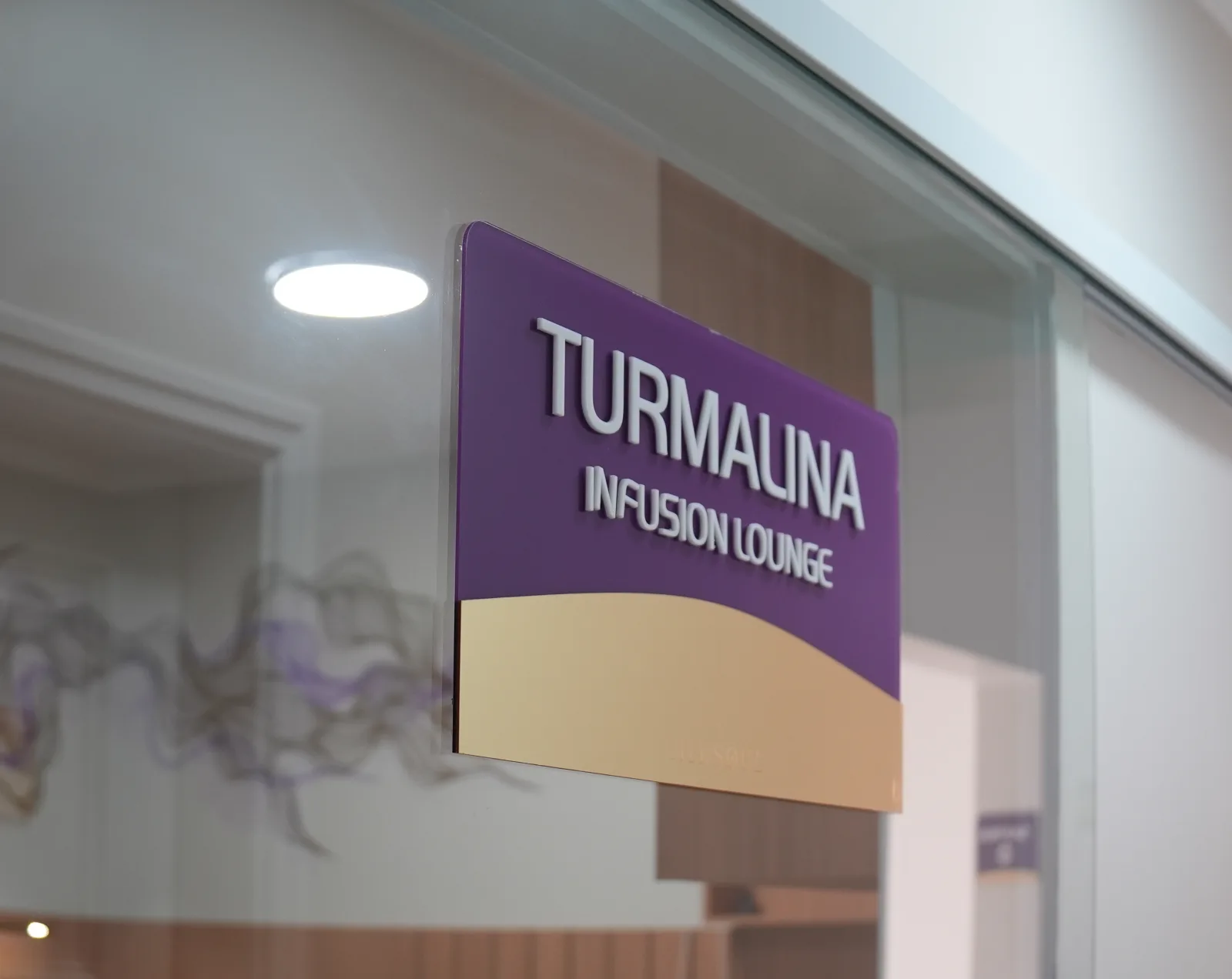 Placa Turmalina Infusion Lounge na parede, no corredor dos consultórios